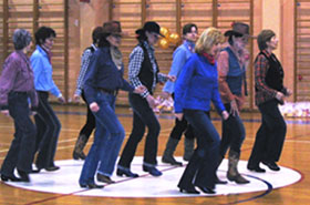 Grupa polaznika pleše Line Dance u kaubojskim šeširima u dvorani